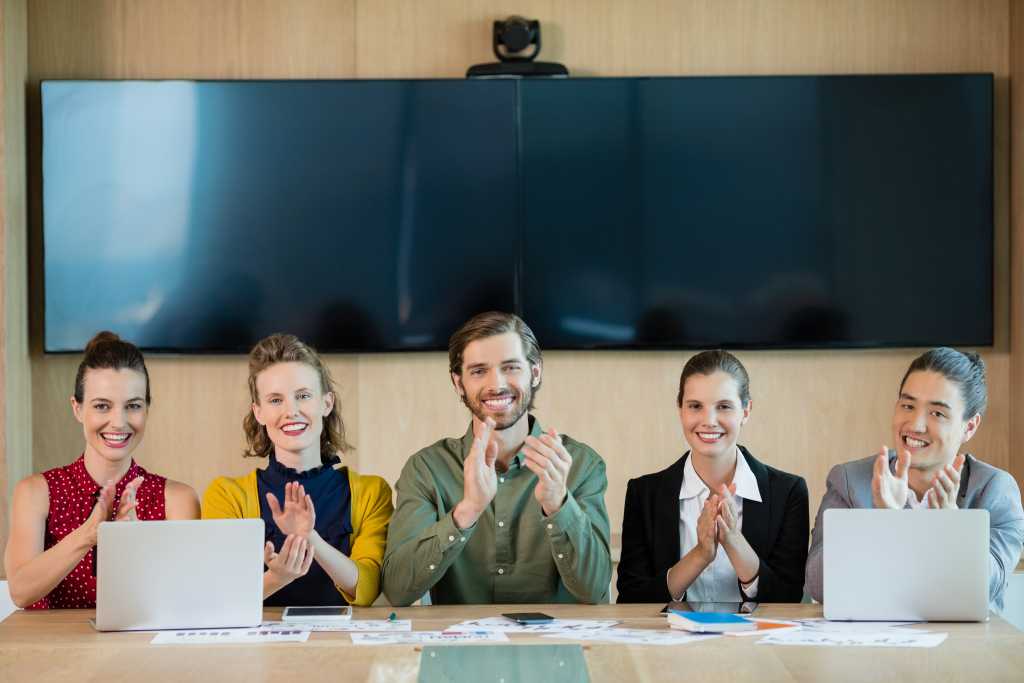 Smiling business team applauding during meeting in conference room