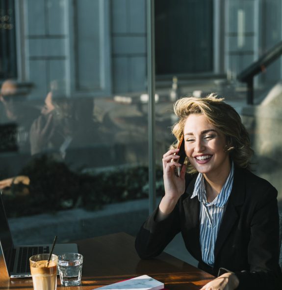 happy-businesswoman-sitting-restaurant-using-mobile-phone